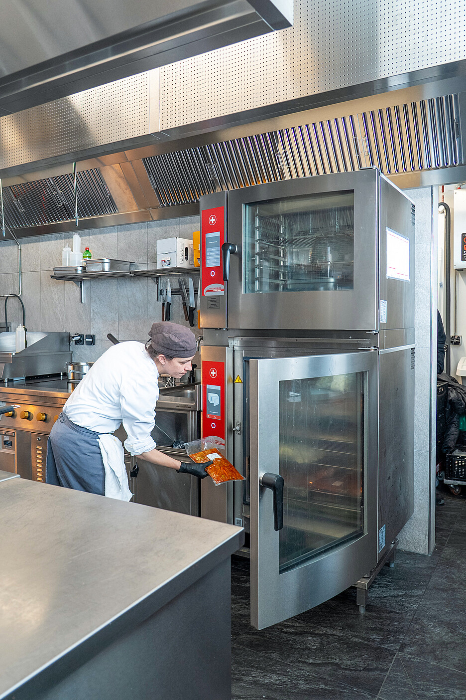 Des collaborateurs régénèrent des plats sous vide dans deux grands combisteamer de Hugentobler Système de cuisson suisse.