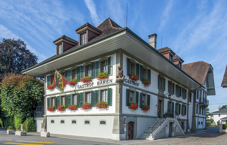 À l’entrée de l’établissement, un ours lève la patte comme pour saluer les visiteurs. Bienvenue au Bären d’Utzenstorf, dans le canton de Berne. Cette auberge de campagne, forte de plus de deux siècles d’histoire, déploie ses charmes à travers plusieurs salles, un jardin intime et une terrasse accueillante. Le lieu se prête aussi bien aux repas quotidiens qu’aux grandes fêtes.