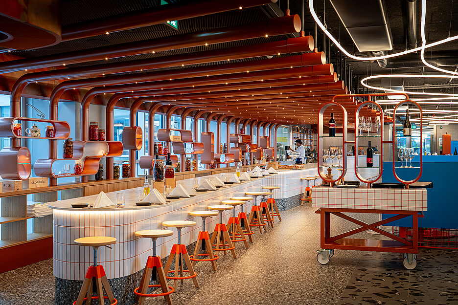 Le restaurant à la carte avec ses cuisines ouvertes. La décoration a été réalisée par une entreprise établie du secteur de la construction en collaboration avec un collectif de jeunes.