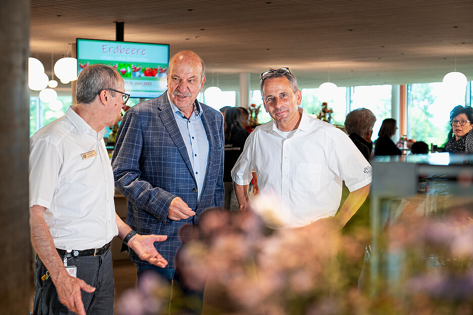 Reto Garbely (à droite), responsable de la restauration au Centre suisse des paraplégiques de Nottwil, a opté à plusieurs reprises pour la solution de distribution des repas de Beat Schmalz (au centre), propriétaire et directeur de Schmalz Distributions-Systeme AG. Ici en conversation avec Ilidio Manuel Silva Machado, chef de service.